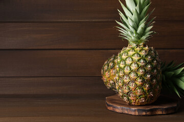 Whole ripe pineapples on wooden table, space for text