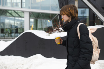 Cute teenage girl with takeaway coffee cup on winter day. Teenager kid drinking hot beverage on...