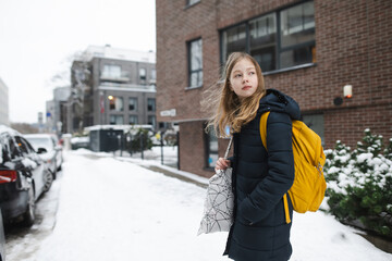 Cute young girl with a backpack heading to school on cold winter morning. Child going back to school.