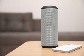 Portable bluetooth speaker and smartphone on wooden table indoors, space for text. Audio equipment