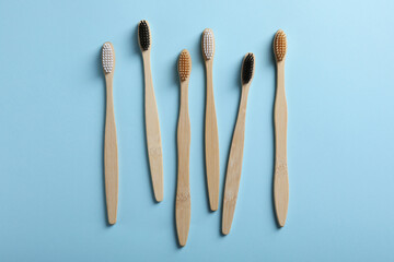 Bamboo toothbrushes on light blue background, flat lay