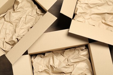 Open cardboard boxes with crumpled paper on wooden floor, flat lay. Packaging goods