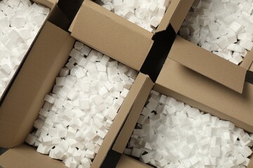 Open cardboard boxes with pieces of polystyrene foam on floor, flat lay. Packaging goods - obrazy, fototapety, plakaty