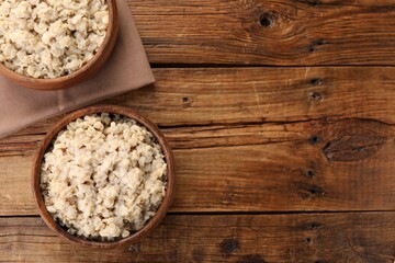 Tasty boiled oatmeal on wooden table, flat lay. Space for text