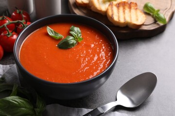 Delicious tomato cream soup in bowl on grey table, closeup