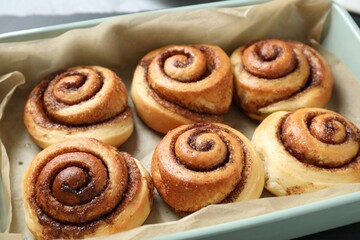 Baking dish with tasty cinnamon rolls on table, closeup