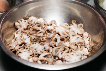 Small raw octopuses in a bowl. Defrosted thawed cephalopods. Close-up. Selective focus.