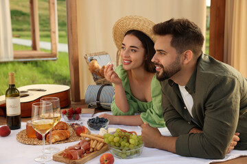 Romantic date. Beautiful couple having picnic in wooden gazebo