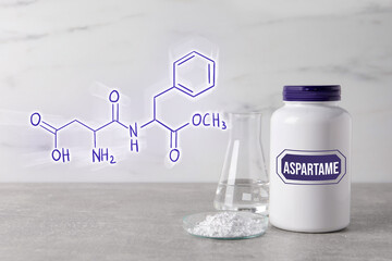 Chemical structural formula of aspartame. Artificial sweetener in petri dish and bottle on gray...