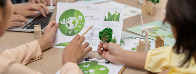 Professional businessman interested in invested in green businesses when he see rising graph on table with environmental document and wooden block scatter around. Closeup. Focus on hand. Delineation. - obrazy, fototapety, plakaty