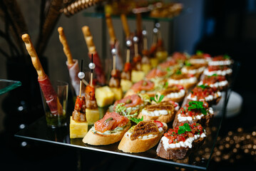 hors d'oeuvres on a glass table. Salsa, salmon, tomatoes, mozzarella, and a variety of cheese canapés. catered luxury. - obrazy, fototapety, plakaty