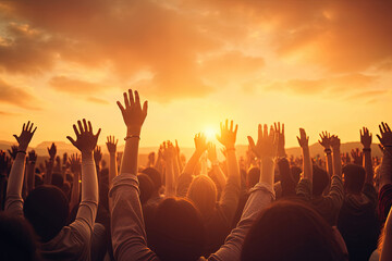 Worship and praise concept: Christian people raising their hands in a unified crowd at sunset - obrazy, fototapety, plakaty