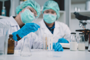 Food scientist or two researcher testing milk samples of dairy products in the laboratory. Researchers are looking and compare at the stratification of milk.