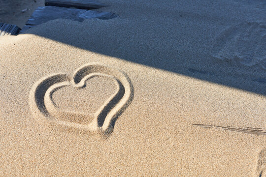Heart drawn in the sand on the beach, closeup of photo