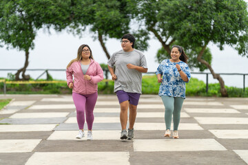 Overweight friends jogging along a public park