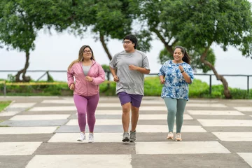Zelfklevend Fotobehang Overweight friends jogging along a public park © Guillermo Spelucin