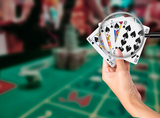 Playing poker cards in hand isolated on Casino background with green table. Flush Winning Gambling...