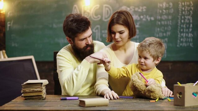 Boy from elementary school. Parents teaching children. Family in early development concept. Father mother and child son painting together at home.