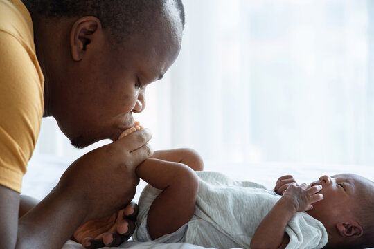 Close up, African father kisses newborn son's feet, newborn baby 15 days, African family and newborn concept, father's day
