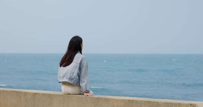 Woman sit outside and look at the sea