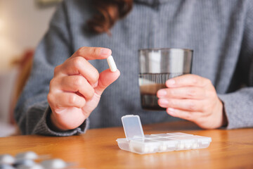 Closeup image of a woman holding pills and a glass of water