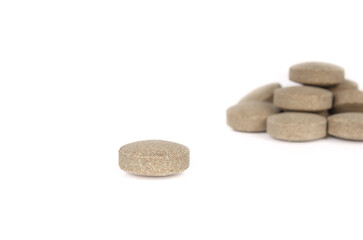 Fototapeta na wymiar Round wafer tablet with defocused pile. Multiple green textured pressed tablets or pills. Isolated multivitamins for dogs, food supplement. Selective focus. White background.