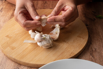 Fototapeta na wymiar Concept of handling food, Female hands preparing garlic, on a cutting board to season food