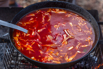 Appetizing borscht in a cauldron on fire. Traditional soup of Russian and Ukrainian cuisines....