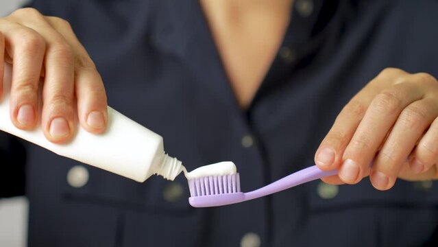 Young woman applying toothpaste on toothbrush.