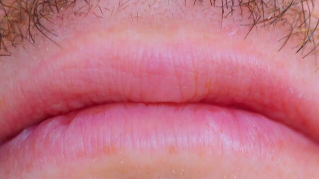 Close-up of part of a man face at the mouth. Lips and slightly regrown stubble.