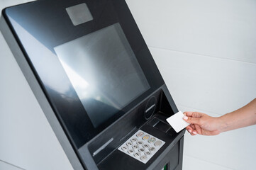 A faceless woman inserts a credit card into an ATM. Close-up of a woman's hands using an ATM machine.