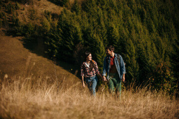 Fototapeta premium A diverse couple joyfully hiking on a sunny day, with backpacks in tow