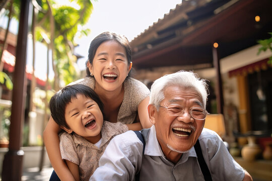 Meeting of grandfather and grandchildren. An elderly Asian man and his grandchildren are happy together. They hug and rejoice at meeting each other. Caring for the elderly. Children visit old people.