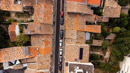 Above a small street in Montpellier, France. Red tiled roofs faded from the sun. Cars line the...