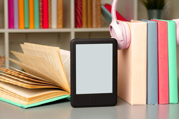 E-book reader on table against book shelves