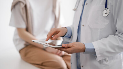 Doctor and patient in clinic. Friendly physician using tablet computer near a young woman. Medicine...