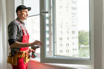 Worker installs windows master sverdit frame to attach to the base repair in high-rise building © Angelov