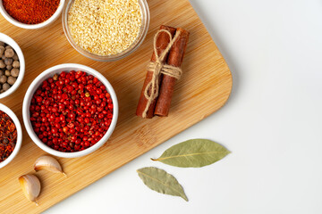 Bowls with spices on wooden board on white background
