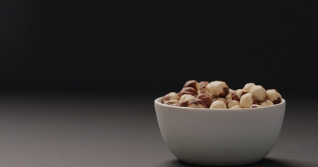 roasted hazelnuts in white bowl on black background