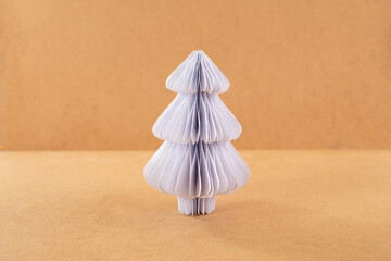 a paper symmetrical shape christmas tree sitting on top of a table, brown and white color scheme,...