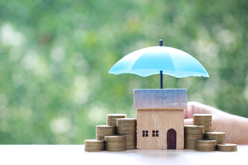 Protection, Model house and  stack of coins money with the umbrella on nature green...