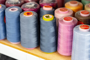 Row of multicolored thread spools at sewing factory