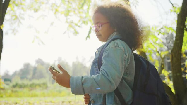 African American schoolgirl with smartphone outdoors