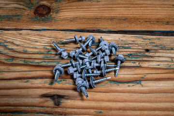 Group of roofing screws on a wooden texture background