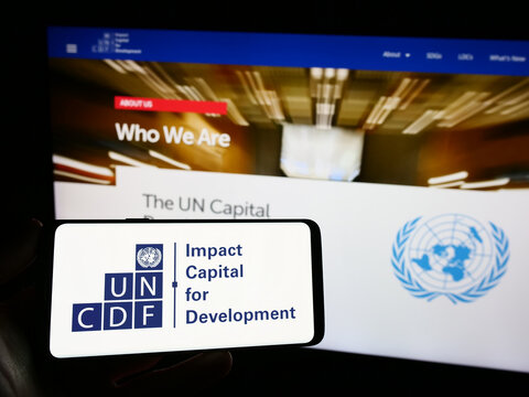 Stuttgart, Germany - 09-25-2023: Person holding smartphone with logo of United Nations Capital Development Fund (UNCDF) in front of website. Focus on phone display.