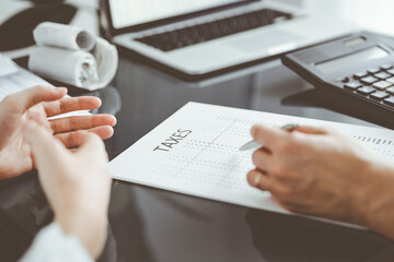 Woman accountant using a calculator and laptop computer while counting taxes for a client. Business...