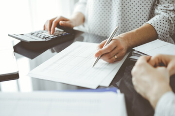 Fototapeta na wymiar Woman accountant using a calculator and laptop computer while counting taxes for a client. Business audit and finance concepts