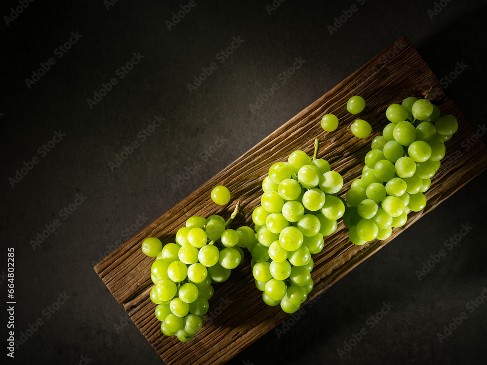 Sticker shine Muscat, green grapes on a wooden tray