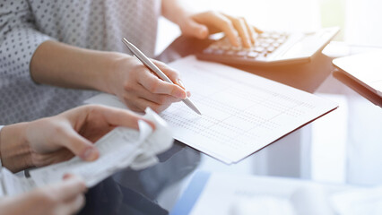 Woman accountant using a calculator and laptop computer while counting taxes with a client or...