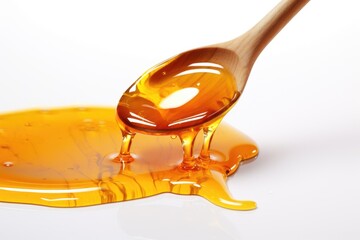 Honey dripping from a spoon on a white background. Puddle of honey. - obrazy, fototapety, plakaty